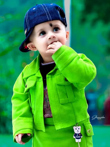 A stylish little boy in a bright green jacket, lost in thought. This baby portrait showcases how I use vibrant colors and natural light to create memorable and cute baby photos.