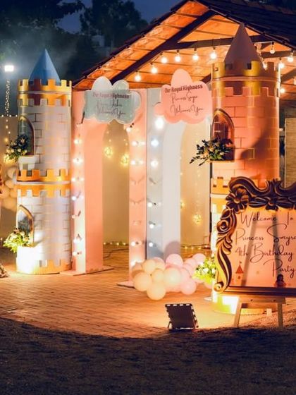 A magical castle entrance lit up at night for Smyra and Dishir's royal birthday. The twin castle turrets and ornate welcome signs create a truly enchanting atmosphere.