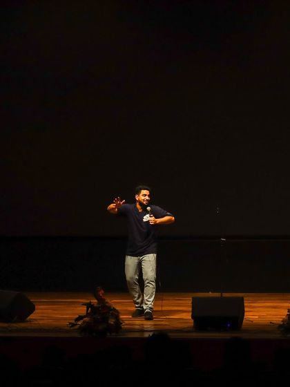 A wide shot of Samay Raina on the minimalist stage at MIT Bengaluru, proving that a great comedian needs nothing more than a mic to entertain a huge crowd.