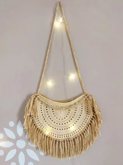 This is the Callaia Bag, a beautiful half-moon shaped sling with a boho-chic vibe, complete with long fringe and beaded details.