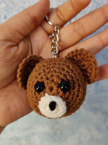 A close-up of my grizzly bear keychain. The detailed embroidery on the face gives it a sweet and friendly expression, making it a lovely accessory for your keys or bag.