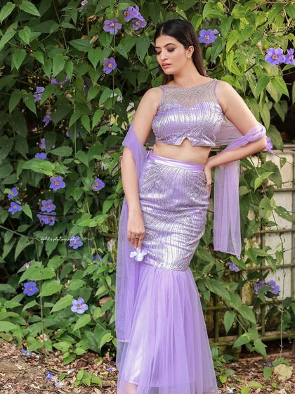 A designer shoot for a modern lavender lehenga. The images were taken in a lush garden, with the purple flowers complementing the color of the outfit, creating a soft and romantic fashion story.