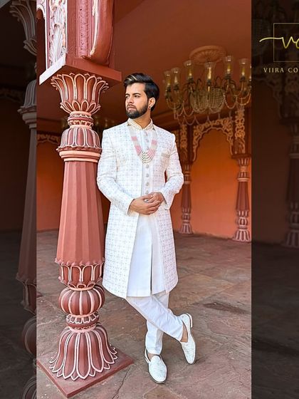 An elegant white sherwani with intricate self-embroidery, paired with a matching necklace. A regal choice for the main wedding ceremony.