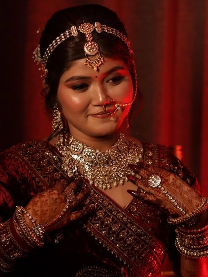 Adjusting her stunning diamond and pearl jewelry. This close-up shows the intricate details of her bridal accessories and the flawless makeup application.