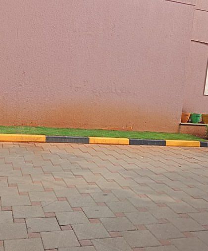 A work-in-progress shot of a commercial landscape project, showing the initial stages of laying turf along a paved area.