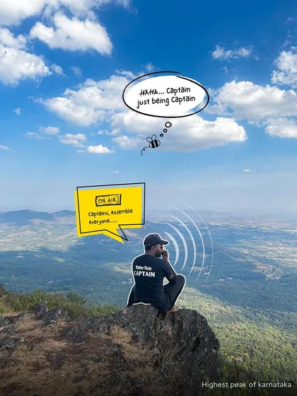 A trip captain sits on the highest peak of Karnataka in Chikmagalur, coordinating the group. This image shows the dedication and fun spirit of my team.