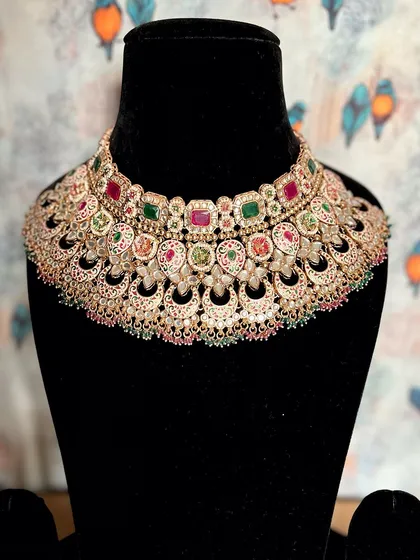 A closer look at the artistry of Meenakari. This beige Kundan necklace with ruby and emerald stones is perfect for adding a splash of color and regal elegance to your bridal or festive outfit.