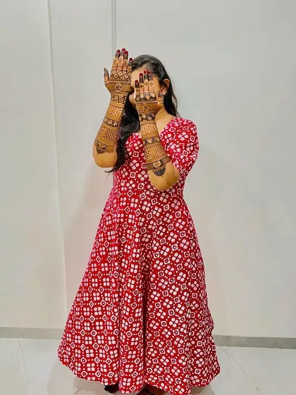 A happy bride playfully showing off her beautiful, detailed mehndi.