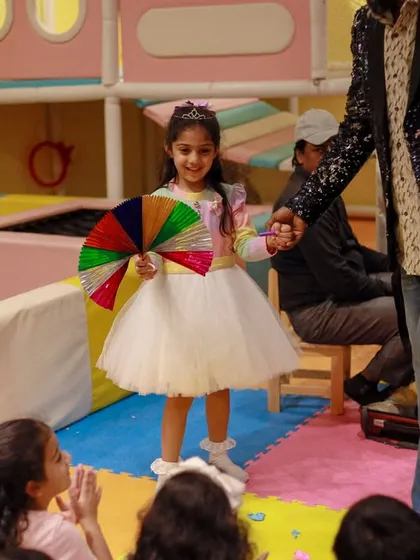 The birthday girl participates in a magic show, holding a colorful fan. We love to make the guest of honor a part of the entertainment.