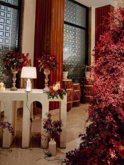 Another cozy and well-lit corner, combining modern white furniture with rustic wooden barrels and dramatic red foliage.