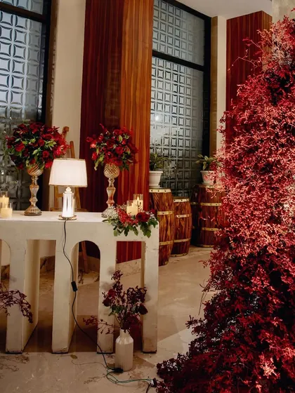 Another cozy and well-lit corner, combining modern white furniture with rustic wooden barrels and dramatic red foliage.