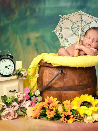This colorful, vibrant setup features a newborn in a wooden bucket surrounded by sunflowers and other bright props, perfect for a cheerful announcement.