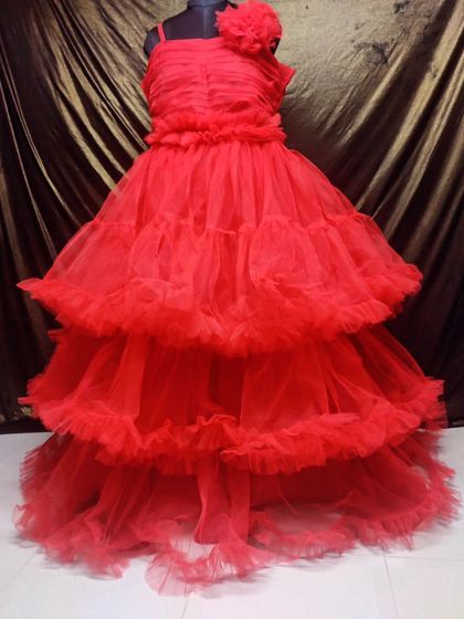 A classic red ball gown with a one-shoulder floral detail. The tiered, ruffled skirt adds plenty of volume, making it a perfect rental for a pre-wedding shoot or formal event.
