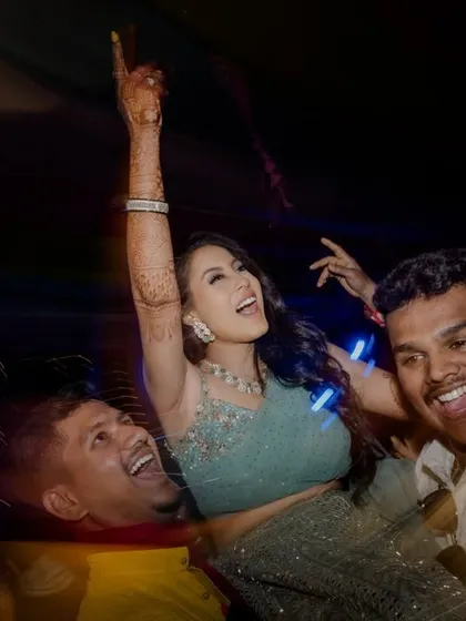 The bride is lifted up on the dance floor, a moment of pure, uninhibited joy during the Sangeet party.