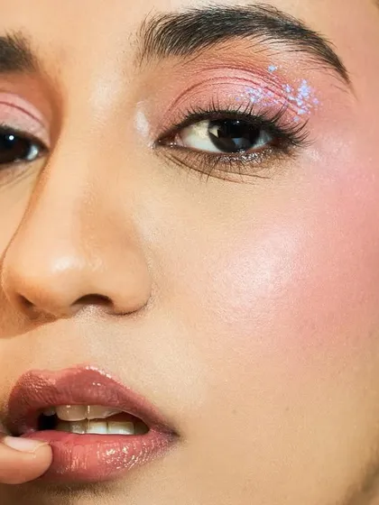 A close-up showing the interplay of textures. The glossy lip, glowing skin, and sparkling eye come together for a fun and glamorous look.