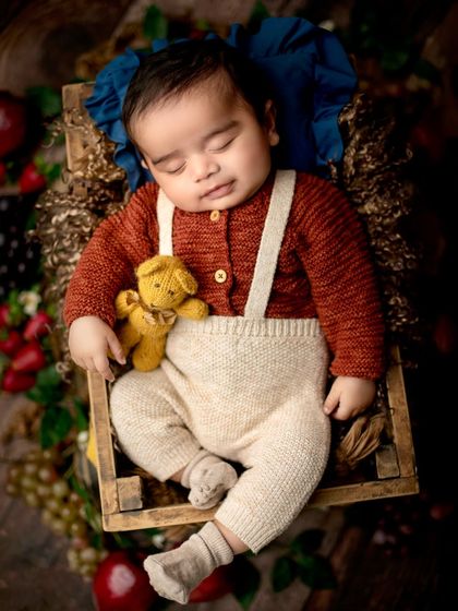 A closer view of the autumn-themed portrait, focusing on the baby's peaceful face and the texture of his knitted cardigan.