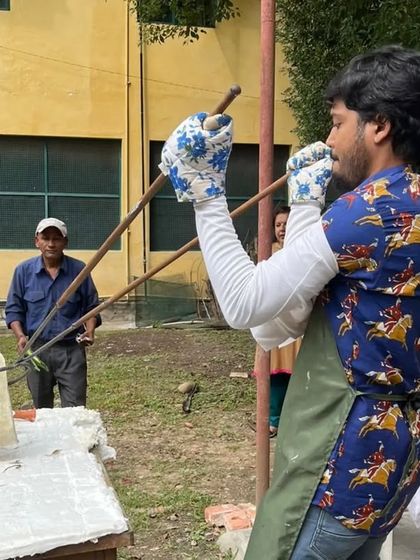 A student carefully holds a hot sculpture with tongs during a Raku workshop. This hands-on experience is central to understanding the process.