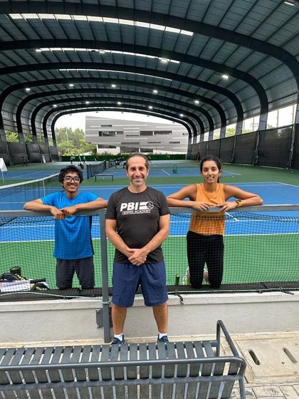 A coach poses with two of our athletes on the court. Our coaching philosophy is built on creating strong, personal connections with each player to help them achieve their individual goals.
