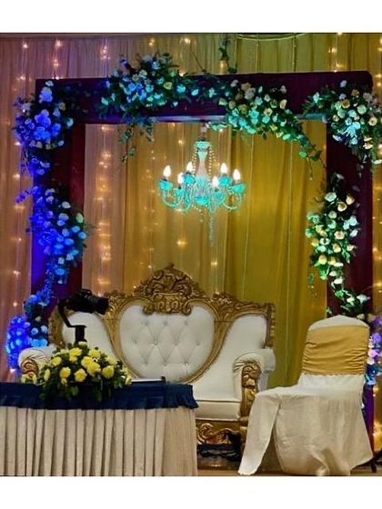 A vibrant mix of colors and elements for a lively celebration. This stage combines a floral arch, a beautiful blue chandelier, and dramatic uplighting to create a festive and eye-catching setup.