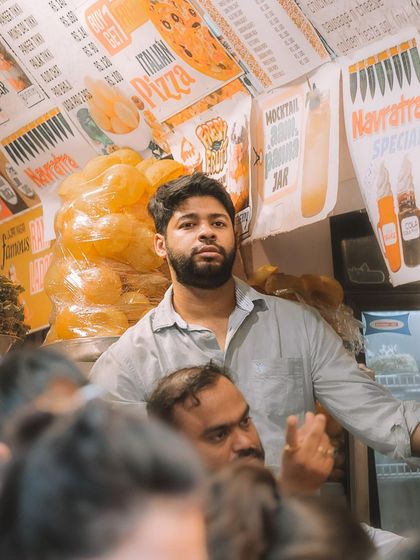 A shopkeeper at a food stall in Lajpat Nagar, captured between serving customers. I aim to document the everyday faces and lives that make up the city's fabric.