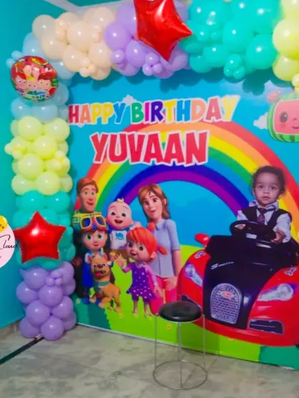 A full-wall Cocomelon birthday backdrop with character prints and a colorful balloon frame.