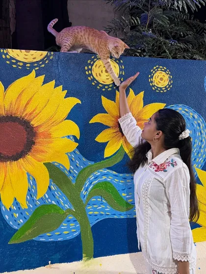 Here I am with a finished custom piece, a reinterpretation of Van Gogh's 'Starry Night' with bright sunflowers. Even a friendly cat couldn't resist taking a closer look.