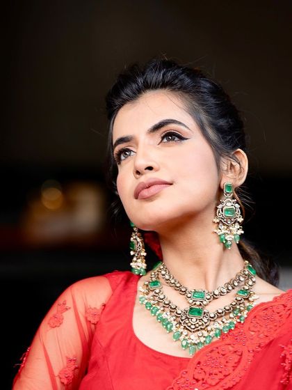 A stunning portrait of our model Harsha. She is wearing a layered Victorian necklace set with beautiful green stones, paired with a vibrant red saree for a striking contrast.