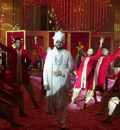 The groom's entry is the start of the varmala sequence. Here, he makes a confident entrance, flanked by dancers in coordinated red outfits, building excitement for the bride's arrival.