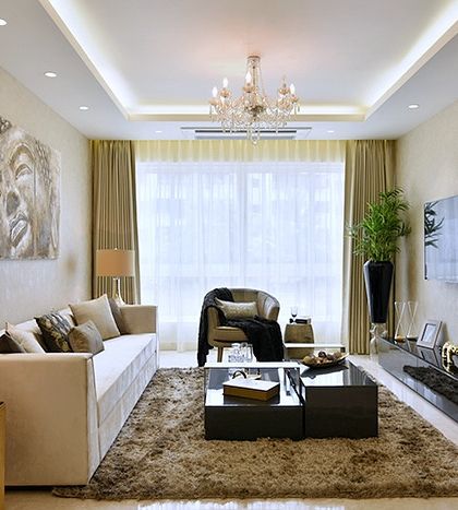 This opulent drawing room uses a palette of beige and muted tones to create a feeling of royalty. The large Buddha artwork adds a sense of serenity, while the plush rug and layered lighting make it feel cozy.
