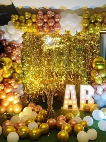A beautiful backdrop for any birthday, featuring a gold sequin wall and a balloon arch in rose gold, gold, and white. The light-up initials add a personal touch.