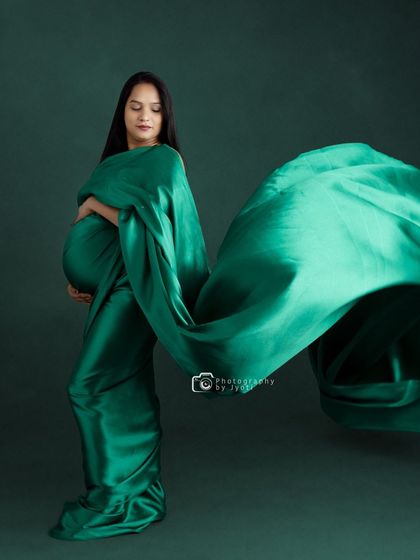 A dramatic studio shot with a flowing emerald green fabric, creating a sense of motion and elegance.