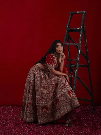 A full-length shot of a bride in a magnificent red lehenga, showcasing a complete and regal bridal look.