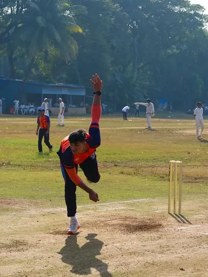 A bowler running in to deliver the ball during the practice match, with an umpire and batsman in position.