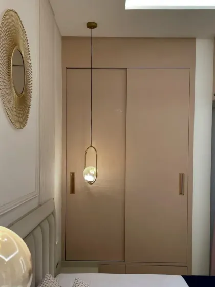 This image showcases the sliding wardrobe and the unique gold-toned circular mirror, adding a touch of glamour to the bedroom's decor.