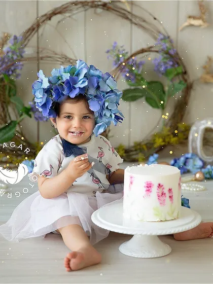 My collection includes everything you need for a cake smash session. This photo shows a white ceramic cake stand, a blue floral crown, and a backdrop decorated with rustic grapevine wreaths.