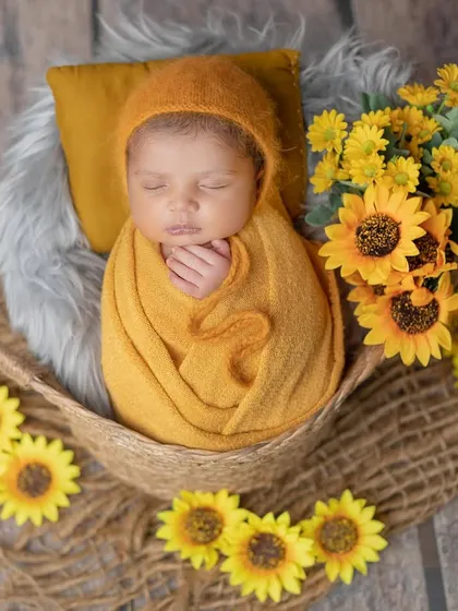 Wrapped in a warm mustard color and surrounded by sunflowers, this newborn looks so cozy.