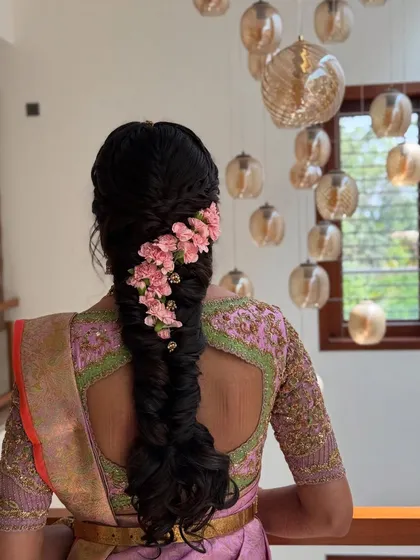 For a softer, more romantic bridal style, I designed this intricate fishtail braid adorned with a cascade of delicate pink flowers. This look is perfect for pre-wedding events like an engagement or sangeet, blending traditional braiding techniques with a modern floral touch.