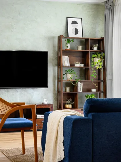 The 'Wind-chime' living room, where a dark wood bookshelf and TV unit are set against a textured green wall, creating a cozy and moody atmosphere.