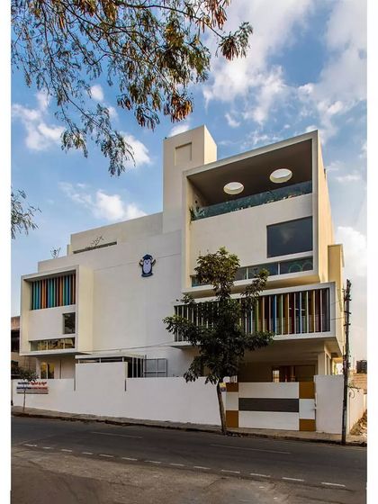 The 'Toy Story' preschool building, designed to be a playful and imaginative space for young children. The facade features colorful vertical louvers and a large, cantilevered volume with circular cutouts, creating a building that looks like it's ready for fun.