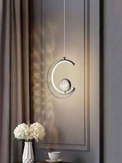 A crescent-shaped pendant with a crystal-dusted sphere. This celestial-inspired light is perfect for a bedroom or a quiet reading nook.