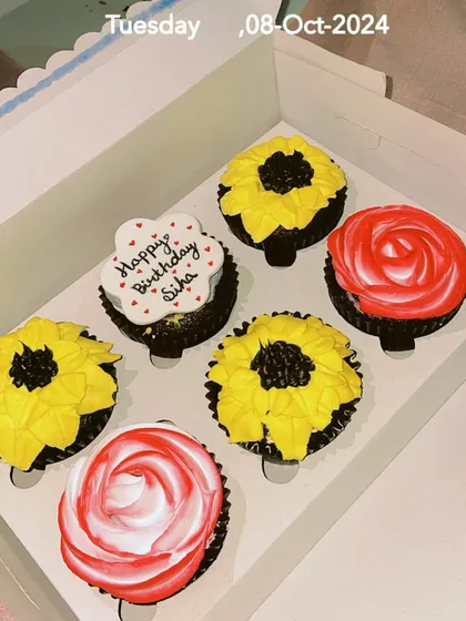 A custom box of six eggless cupcakes designed for a birthday. This set features hand-piped sunflower and rose designs, along with a personalized cupcake with a 'Happy Birthday' message. I can create themed cupcake boxes for any occasion.