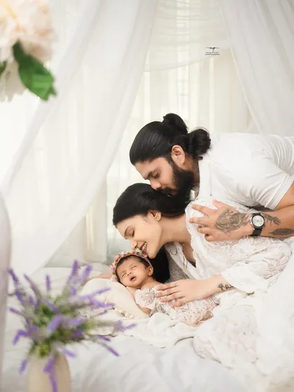A serene and intimate portrait of new parents embracing their sleeping newborn. This light and airy style, set against a clean white backdrop, highlights the pure, peaceful connection of a new family.