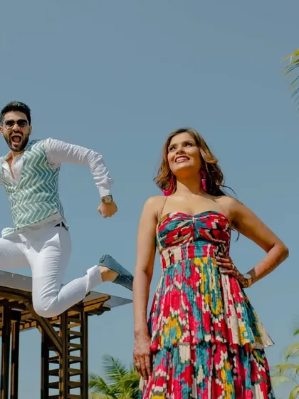 A fun and dynamic shot of the groom jumping for joy while his bride strikes a pose. Their happiness is our priority.