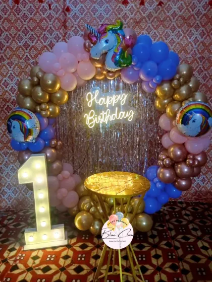 A unicorn-themed first birthday with a balloon ring, shimmer backdrop, neon sign, and a light-up number '1'.