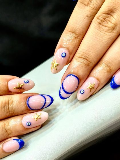 Good vibes only with this evil eye and starfish combo. This set features a sheer pink base with blue French tips, abstract lines, and gold starfish accents.