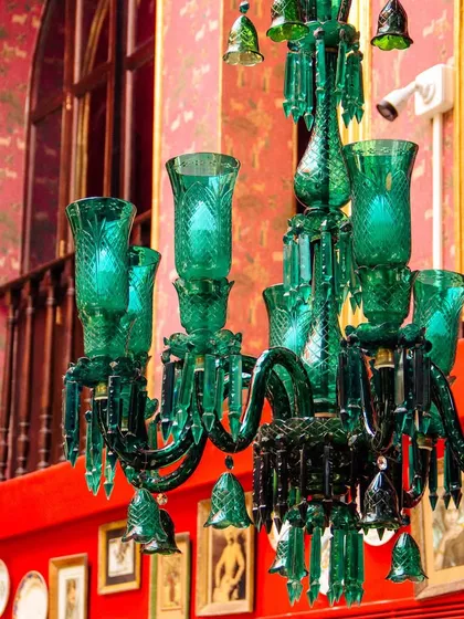 An emerald green chandelier makes a striking statement. These custom pieces are central to our design, swaying like dreams and whispering tales of royal splendor.