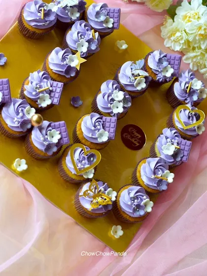 For a special birthday, I arranged these purple-frosted cupcakes into a heart shape. Each cupcake is decorated with small chocolate bars, edible hearts, and delicate sugar flowers.
