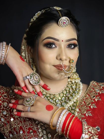 A classic red bridal lehenga look, focusing on the placement of heavy jewelry and the traditional red bindi.