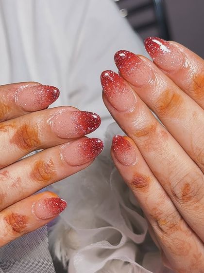 A beautiful red glitter ombre on almond-shaped nails, a simple but stunning choice for any festive occasion.