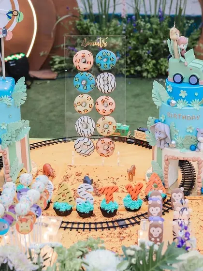 The dessert table was a wild adventure in itself, with two stunning cakes and an array of animal-themed treats set against a custom backdrop, complete with a miniature train track.